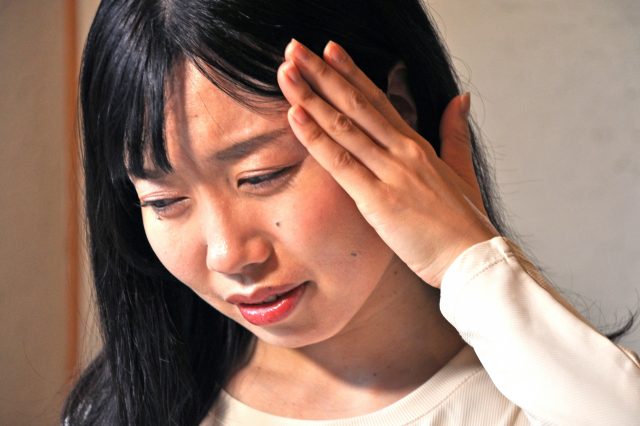 女性が側頭部に手をあてる写真（西宮市整体あいば健整院）