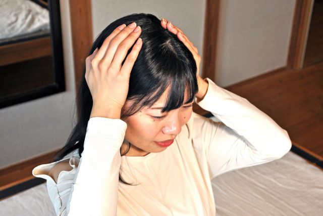 あたまを押さえている女性の写真